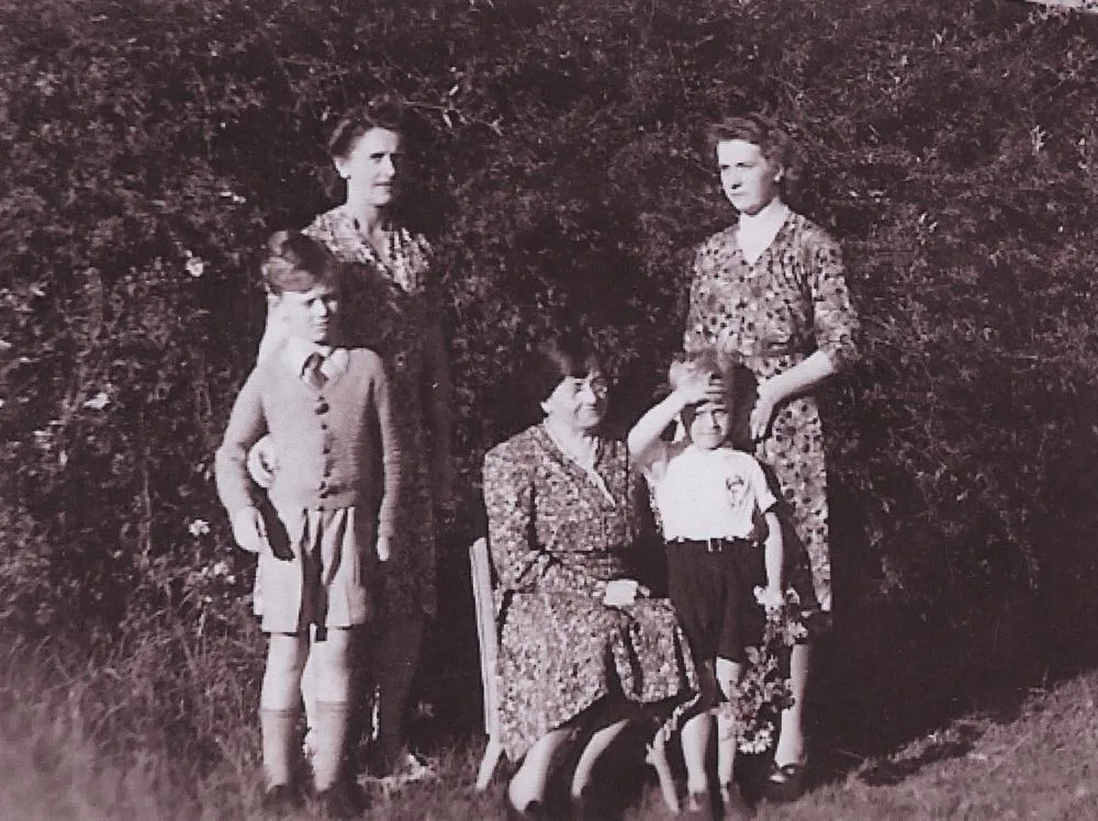 Three generations in a garden in 1942: an older woman seated, two women standing behind her and two small boys beside her.